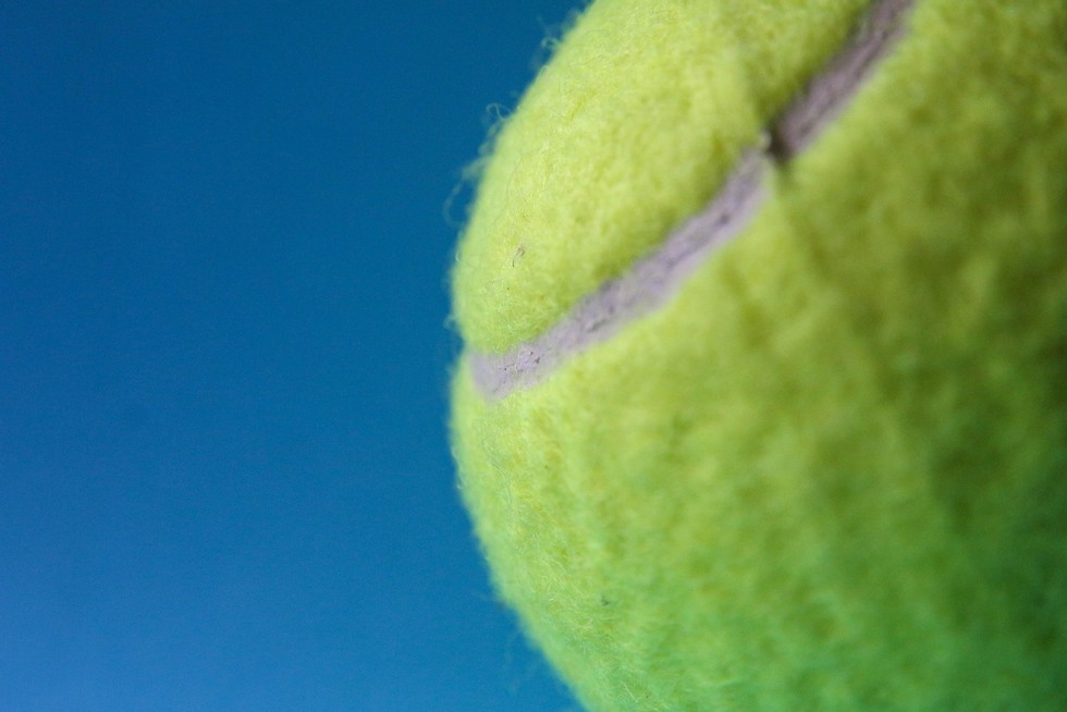 Gelber Tennisball auf blauem Hintergrund als Symbol für Resilienz