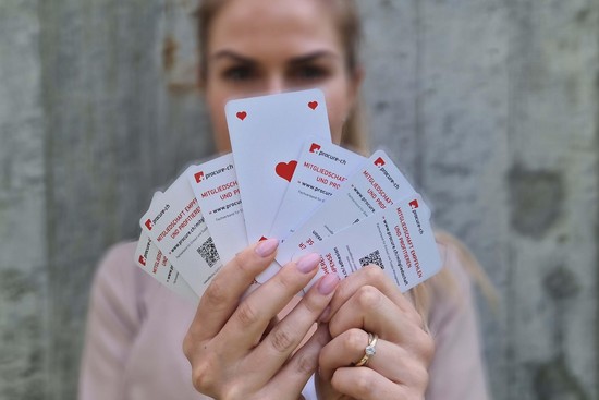 Frau hält Kartenfächer mit der Karte Herz Ass in der Mitte