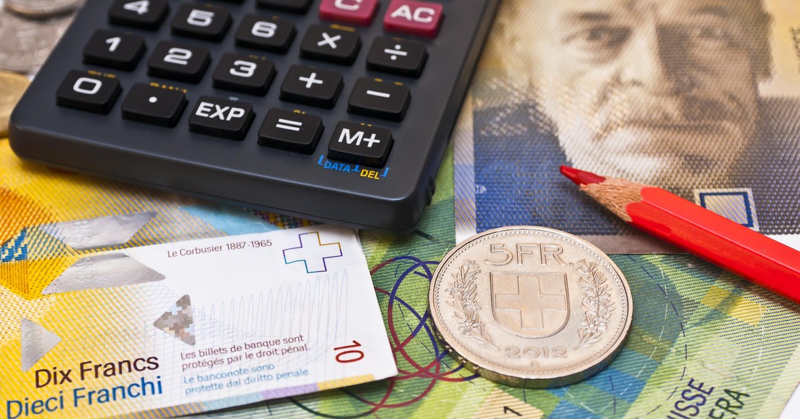 Symbolbild Produzenten- und Importpreisindex, Taschenrechner, roter Bundstift und fünf Franken Münze liegen auf Schweizer Banknoten