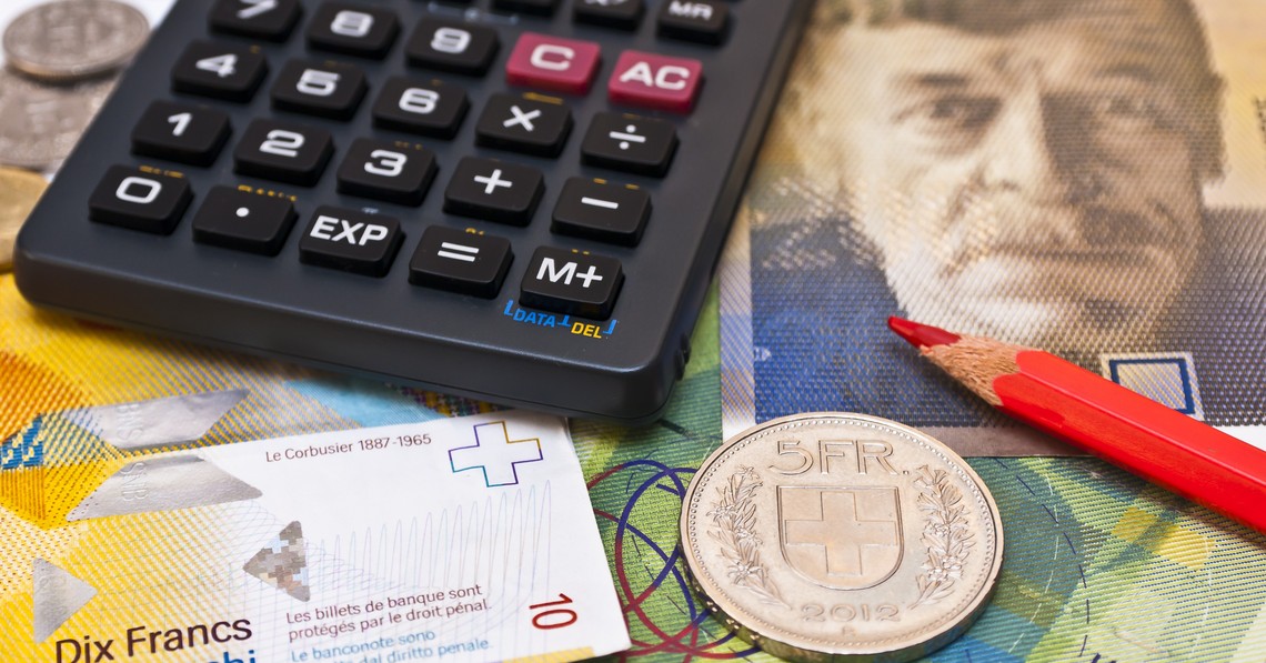 Symbolbild Produzenten- und Importpreisindex, Taschenrechner, roter Bundstift und fünf Franken Münze liegen auf Schweizer Banknoten