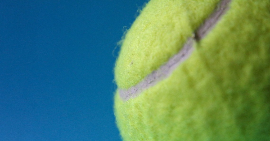 Die Kraft der Resilienz Gelber Tennisball auf blauem Hintergrund als Symbol für Resilienz
