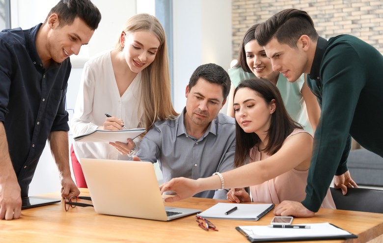 6 Einkaufsfachfrauen und Einkaufsfachmänner schauen zusammen auf einen Laptop und diskutieren