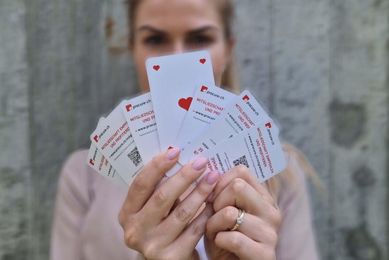 Frau hält Kartenfächer mit der Karte Herz Ass in der Mitte
