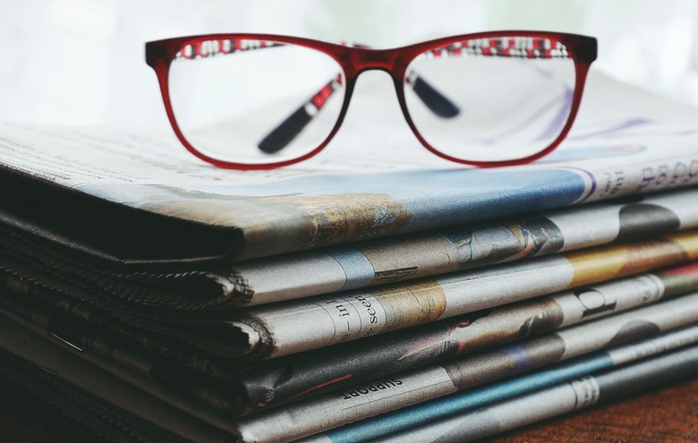 Brille liegt auf Zeitungsstapel 