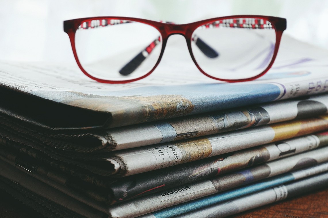 Brille liegt auf Zeitungsstapel 